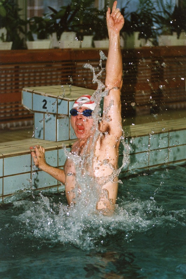 Arkadiusz Pawłowski wyskakuje z wody basenu z ręką w górze w geście triumfu