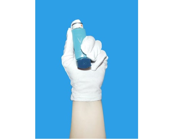 ręka w białej rękawiczce trzyma niebieski inhalator