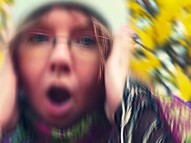 Rozmazane zdjęcie krzyczącej kobiety, która łapie się za głowę