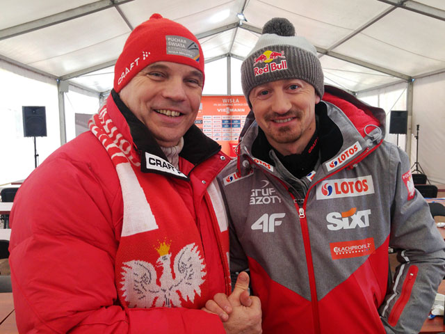 Wnętrze białego namiotu. Od lewej: Krzysztof Głombowicz z Adamem Małyszem. Obaj ubrani na sportowo w czapkach zimowych. 