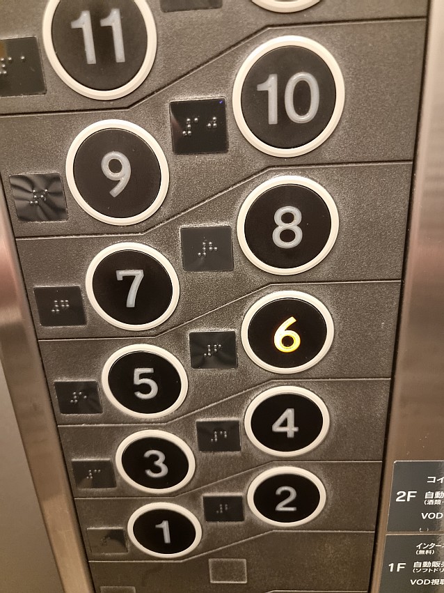 Panel w windzie. Obok klawiszy z numerami pięter są znaki w brajlu