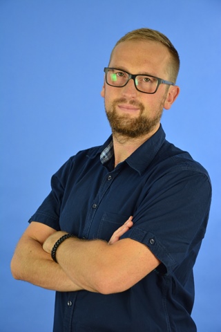 Michał Garncarek mężczyzna około czterdziestoletni w okularach blondyn z założonymi rękami patrzy w obiektyw