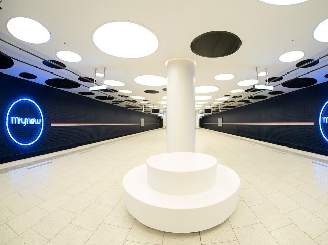 wnętrze metra młynów niebieski neon na ścianach po obu stronach z napisem młynów i białe wnętrze stacji