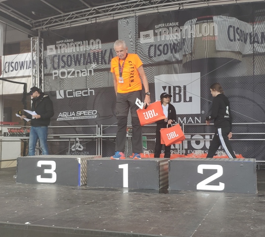 Henryk Michałowski na 1 miejscu podium, delikatnie pochyla się do przodu wykonując ukłon
