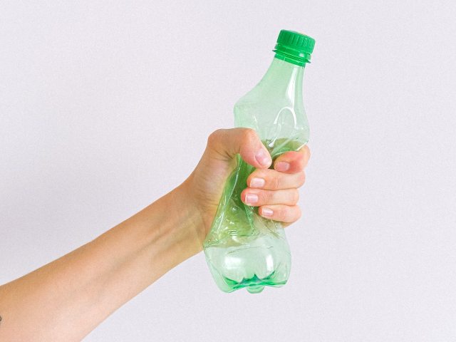 ręka zgniasta plastikową butelkę