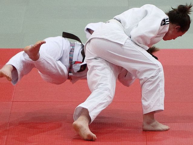Walka judo. Jedna zawodniczka rzuca drugą na matę