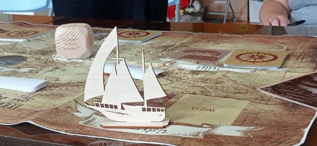 drewniany statek na mapkach, które leżą na stole