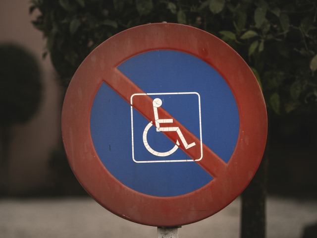 znak zakazu w środku niebieski i biały symbol osoby na wózku przekreślony czerwoną linią