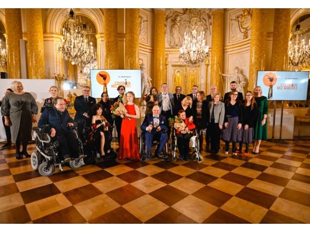 Wszyscy nagrodzeni, wyróżnieni i wręczjaący nagrody w konkursie czlowiek bez barier stoją w rzędach na Sali Balowej na Zamku Królewskim. 