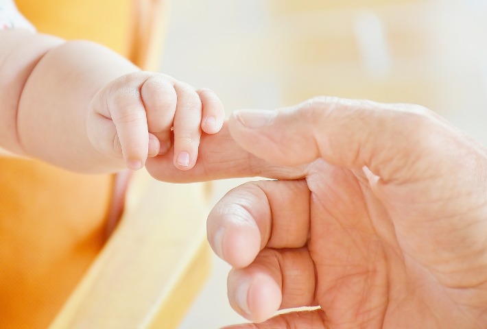 zdjęcie poglądowe. Dłoń małego dziecka trzymająca palec osoby dorosłej.