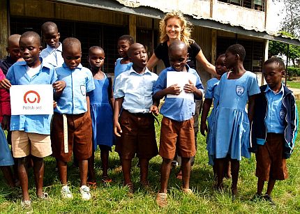 Marta Bielawska stoi w otoczeniu młodych chłopców w Ghanie. Jeden z nich trzyma kartkę z napisem 