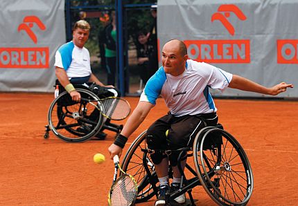 Dwóch mężczyzn na wózkach gra w tenisa na korcie