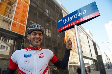 Zbigniew Brzózka na  pasarzu Wiecha przy znaku z napisem ulica Udarowa- czas jest śmiertelnie ważny
