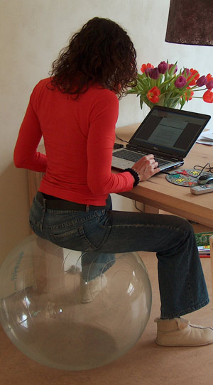 Dziewczyna przed komputerem, siedząca na dmuchanej piłce. Fot.: www.sxc.hu