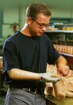 młody chłopak robi protezę stopy, pomagając sobie protezą ręki