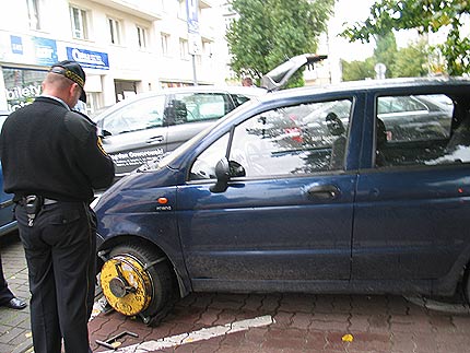 Na zdjęciu: strażnik miejski założył blokadę na auto bezprawnie zaparkowane na kopercie. Fot. CI Gdynia