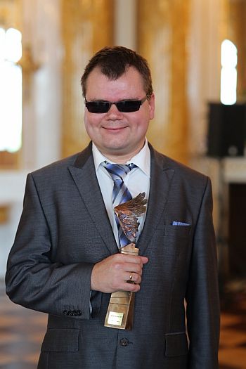 Niewidomy Paweł Ejzenberg stoi ze statuetką 